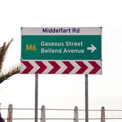 Road sign, intersection and direction in city with arrow for grammar, mistake or text for gas for driving in neighborhood. Buildings, error and funny signage with joke, fart and warning in Cape Town