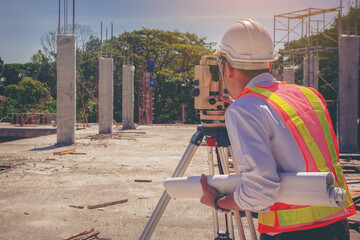Engineer or architecture working with theodolite transit equipment at outdoors construction site.	