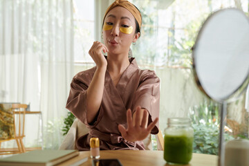 Young woman drying nail polish after doing manicure at home