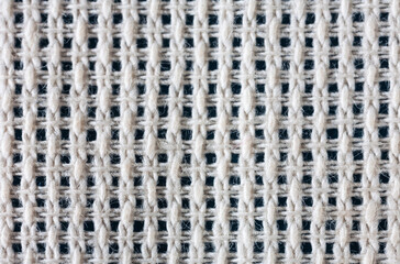 Close-up view of cotton canvas for hand cross stitch or other embroidery. Natural textile background of interwoven threads with square cells. Basis for needlework and hobby. Flat lay, macro, top view