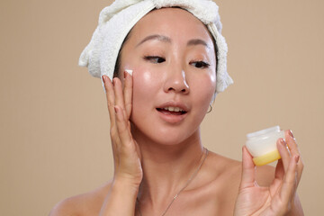Excited woman applying nourishing cream after morning shower