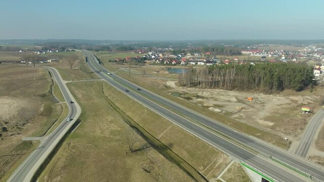 Aerial perspective of a highway near a rural town with construction in the vicinity.
