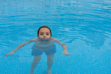 Fototapeta na wymiar boy submerged in the water of the pool, with only his eyes and nose out of the water