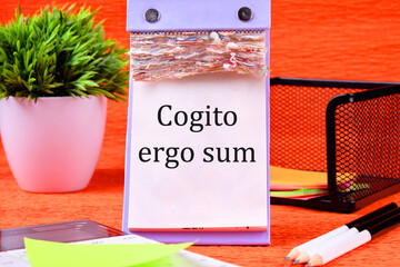 The words Cogito Ergo Sum or I think Therefore I Am It is written on a desktop calendar with loose leaves