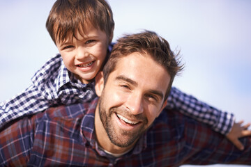 Portrait, man and child with piggy back, smile and playful travel to relax on outdoor adventure. Support, face of father and son in nature for fun bonding, playing and happy trust on holiday together
