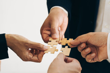 The concept of teamwork and partnership. Businessman's hands putting together puzzle pieces in the office and join together in a jigsaw puzzle team. Charity. Volunteers. Business unity as a team.