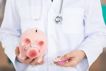 happy young male doctor holding piggy bank