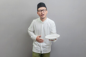Asian Muslim man holding back hunger and plate