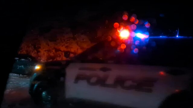 car crash at night in heavy snow with police cruiser attending (rolled off side of snowy mountain road into ditch) flashing lights wet glass traffic accident