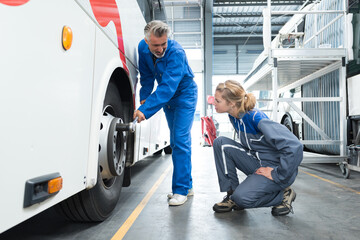 mechanic showing apprentice how to tighten nuts on bus wheel