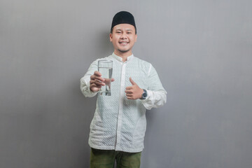 Happy asian muslim man holding glass of pure water give to camera