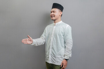 Happy asian muslim man waiving saying hello, friendly welcome gesture - obrazy, fototapety, plakaty