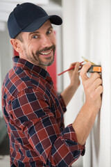 happy man measuring the wall with a measuring tape