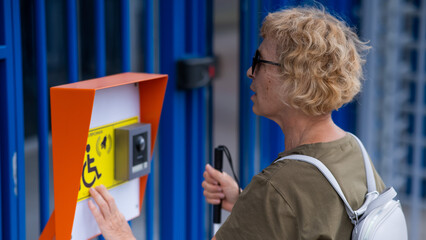 An elderly blind woman reading a text in braille. Button for calling help for people with...