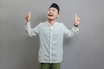 Happy asian muslim man recommend promo as pointing to copy space, indicate down link
