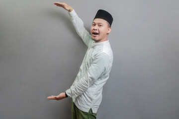 Happy asian muslim man recommend promo as pointing to copy space
