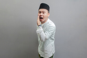 Happy asian muslim man hand on mouth whispering malicious talk conversation