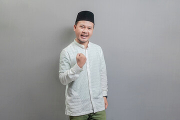 Happy asian muslim man fun successful raised fist hands