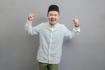 Happy asian muslim man fun successful raised hands show muscles