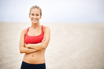 Woman, portrait and fitness on beach sand with arms crossed, confident and smile with wellness and outdoor. Exercise, athlete and sports with happiness for health, marathon or race for cardio workout