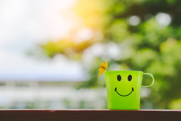 Smiling water glass with flowers on a green background