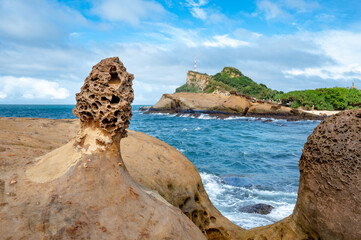 Fototapeta premium Close up on the little mushroom rock next to the coastline, ocean and cape in the distance, background out of focus in purpose, in Yehliu geopark, New Taipei City, Taiwan.