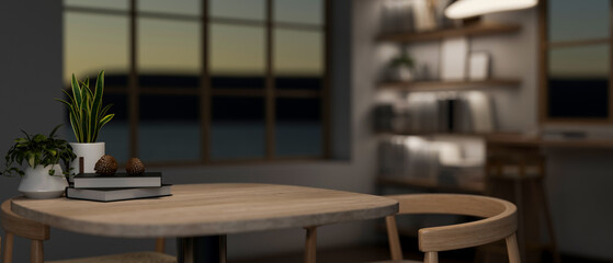 A wooden table with armchairs in a contemporary room at night illuminated by dim lights.