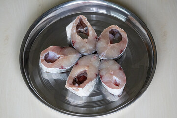 Slices raw Rui fish for cooking on a steel plate isolated on white background. This fish is also...