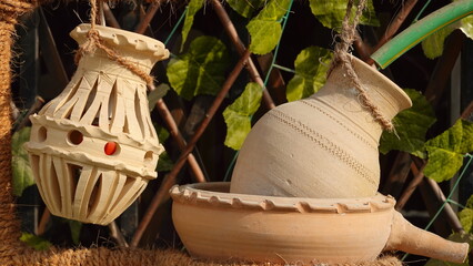 Traditional Clay Objects Elegantly Suspended Against A Natural Vine Background, Capturing The Warm...