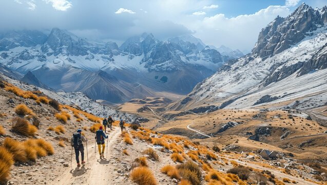 An aerial view of a winding pass through the mountains, with trekkers moving towards a distant basecamp