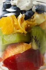 Fruit salad in a glass, transparent jar, on a light background.