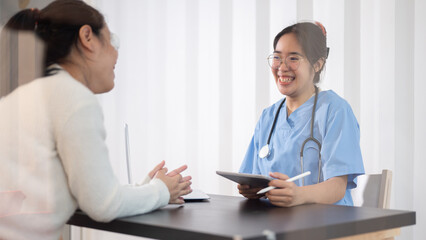 A professional Asian female doctor is consulting a female patient in the office at the hospital.