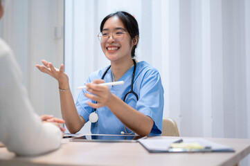 An Asian female doctor is talking with a patient in the office, working at the hospital.