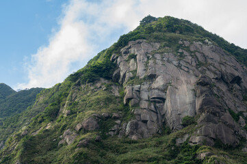 Look up to the mountain, gorgeous rocks make a great cliff, grass growing between the rocks, in Jinguashi, New Taipei City, Taiwan.