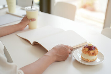 Close up and selective focus traditional british scone with clotted cream and strawberry jam for tea time with hand opening mock up book on table.