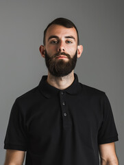 Young man with beard looking calmly at camera in a black polo shirt - obrazy, fototapety, plakaty