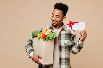 Young man wears grey shirt hold paper bag for takeaway mock up with food products, store gift...