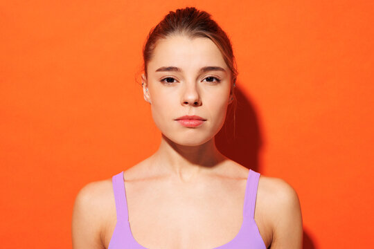 Close up Caucasian young fitness trainer instructor sporty woman sportsman wear purple top clothes spend time in home gym look camera isolated on plain orange background Workout sport fit abs concept