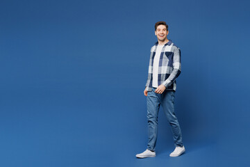 Fototapeta premium Full body side view young smiling satisfied happy man he wears shirt white t-shirt casual clothes walk go look camera isolated on plain blue cyan color background studio portrait. Lifestyle concept.