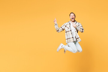 Fototapeta na wymiar Full body young happy Caucasian man he wear brown shirt casual clothes jump high point index finger aside on area mock up isolated on plain yellow orange background studio portrait. Lifestyle concept.