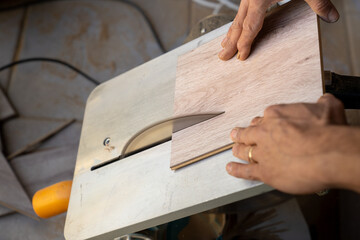 The laminate master man cuts the wooden laminate flooring according to the size on the machine.