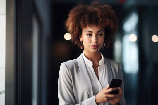 shot of a confident young woman using her cellphone while standing in the office