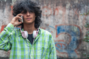 young man with headphones talking on the phone on the street