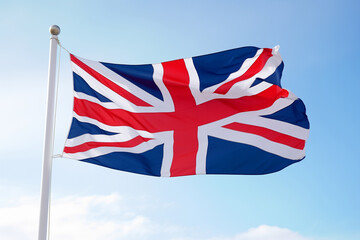 flag of Great Britain on flagpole in wind against blue sky background