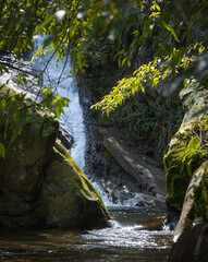 Water slide falling from the big rocks in the background, flowing between two rocks full of moss,...