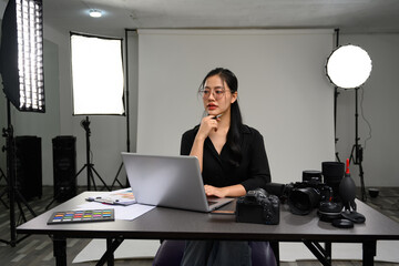 Attractive young woman professional photographer using laptop at table at her studio