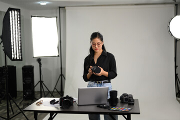 Young stylish woman with her DSLR camera working in professional photo studio