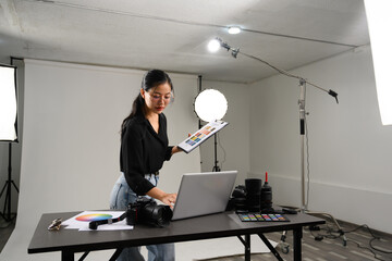 Professional photographer woman using laptop at table in her lighting studio