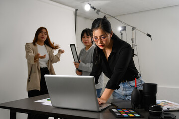 Shot of female photographer working with her team in professional photo studio