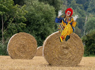 Clown sitz auf Strohballen